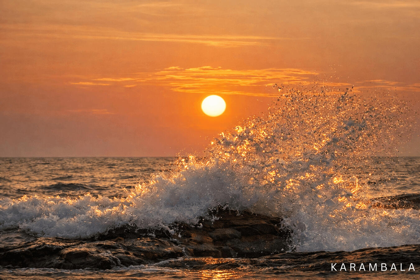 A powerful wave crashes dynamically over the rocks, catching the warm, golden light of a setting sun. A clean and minimalist celebration of Sri Lanka's coastal beauty.